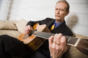 Tony Rice on the couch playing his guitar